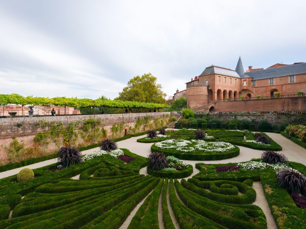 Formaler französischer Garten mit akkurat geschnittenen Hecken und Backsteingebäude.